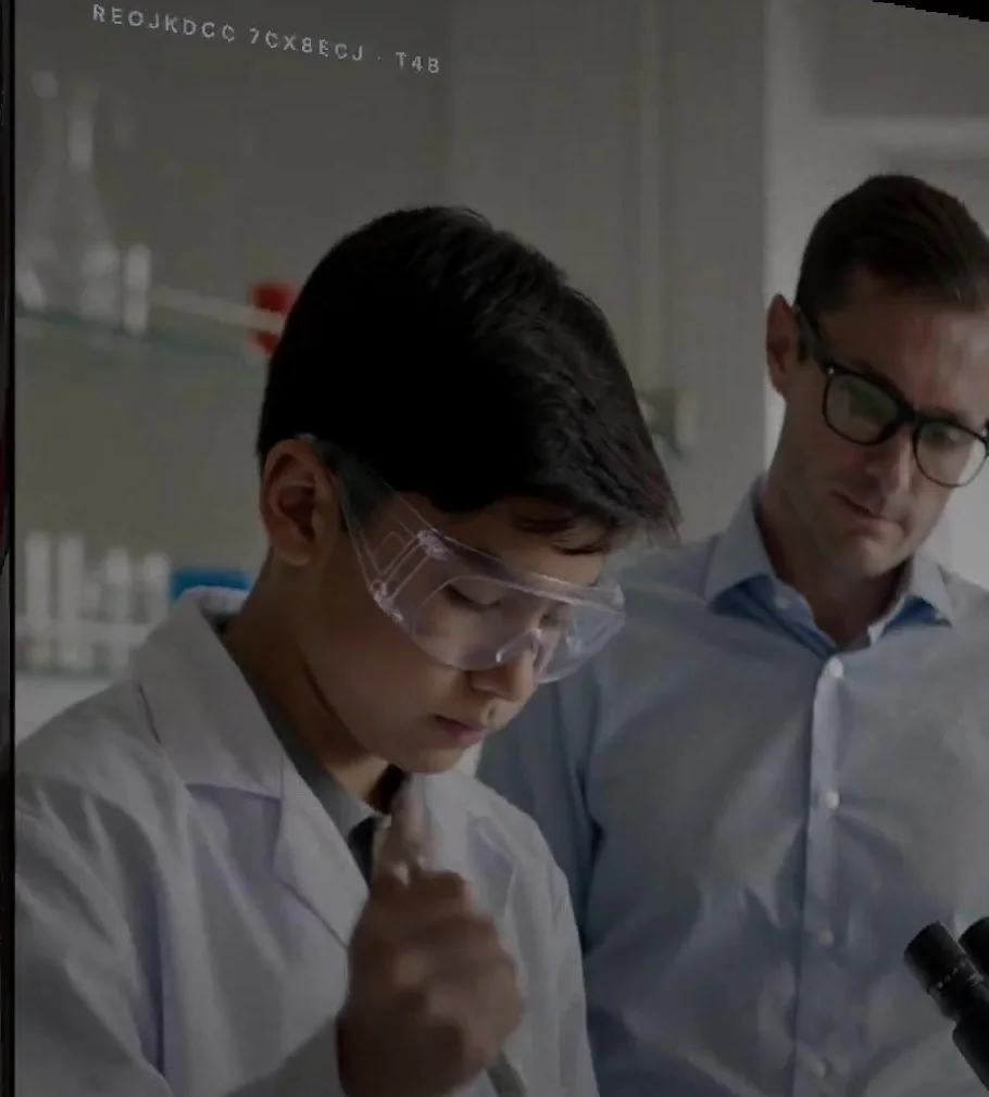 A student in a lab coat working with a scientist