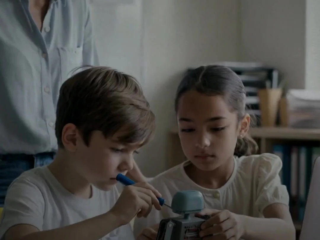 Two children building a small robot with their teacher